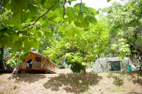 Dos tiendas en una ladera rodeadas de árboles frondosos en Huttopia Sarlat, parque vacacional de Nouvelle-Aquitaine, Francia.