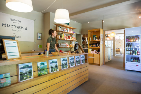 Recepción del parque vacacional Huttopia Sarlat en Nouvelle-Aquitaine, Francia, con personal y tienda.