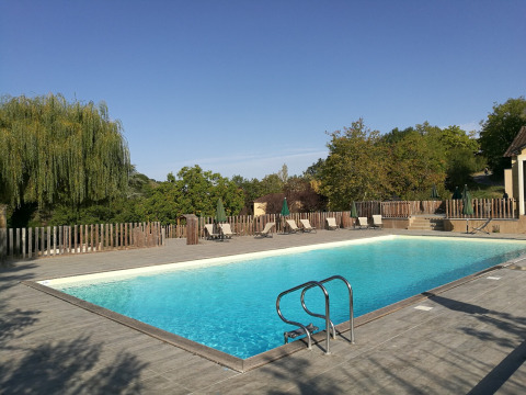 Piscina al aire libre en Huttopia Sarlat, un parque vacacional en Nouvelle-Aquitaine, Francia, rodeada de naturaleza.