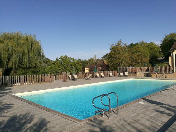 Outdoor swimming pool at Huttopia Sarlat holiday park in Nouvelle-Aquitaine, France, surrounded by nature.
