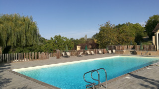 Piscina al aire libre en Huttopia Sarlat, un parque vacacional en Nouvelle-Aquitaine, Francia, rodeada de naturaleza.