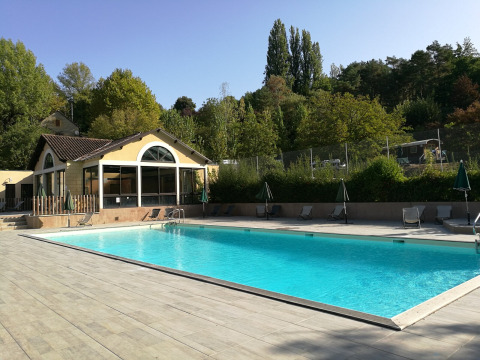 Piscina exterior en el parque vacacional Huttopia Sarlat en Nouvelle-Aquitaine, Francia, rodeada de árboles.