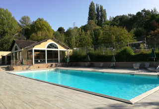 Outdoor swimming pool at Huttopia Sarlat holiday park in Nouvelle-Aquitaine, France, surrounded by trees.