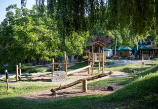 Legeplads i træ og grønne omgivelser ved en feriepark i Nouvelle-Aquitaine, Frankrig, på en solskinsdag.