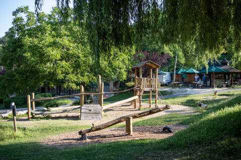 Aire de jeux en bois dans un cadre verdoyant au parc de vacances Huttopia Sarlat, Nouvelle-Aquitaine, France.
