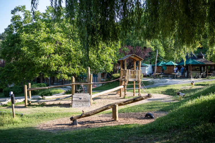 Wooden playground set in lush greenery at Huttopia Sarlat holiday park in Nouvelle-Aquitaine, France.