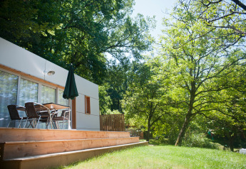 Casa mobile Vancouver presso Huttopia Sarlat in Francia con terrazza in legno, tavolo e natura verde