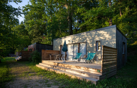Terrasse extérieure du Mobile home Vancouver à Huttopia Sarlat, France, entourée d’arbres et de verdure.