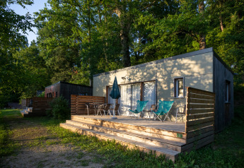 Udendørs terrasse ved Mobile home Vancouver, Huttopia Sarlat, Frankrig, omgivet af grønne træer.
