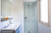 Baño luminoso y moderno en Mobile home Vancouver con ducha, lavabo, espejo y ventana.