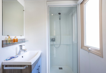 Lyst og moderne badeværelse i Mobile home Vancouver med bruser, vask, spejl og vindue.