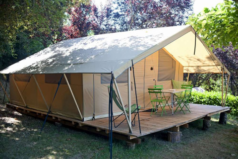 Tente safari Toile&bois Classic chez Huttopia Sarlat en France, vue extérieure avec terrasse en bois devant.
