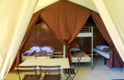 Indvendigt billede af en Toile&bois Classic safari-telt hos Huttopia Sarlat, Frankrig, med senge og bord.