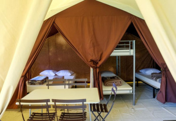 Indvendigt billede af en Toile&bois Classic safari-telt hos Huttopia Sarlat, Frankrig, med senge og bord.