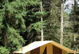 Tienda safari Toile&bois Classic en Huttopia Sarlat, Francia, rodeada de bosque y equipo de acampada.
