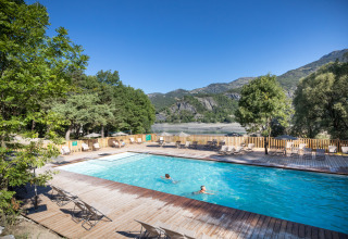 Buitenzwembad met zicht op het meer en de bergen in Huttopia Lac de Serre Ponçon, Provence-Alpes-Côte d’Azur.