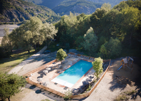 Vista aérea de una piscina rodeada de árboles en el parque vacacional Huttopia Lac de Serre Ponçon, Provenza-Alpes-Costa Azul.