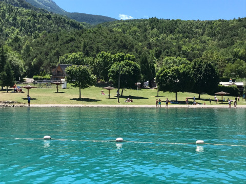 Parque vacacional Huttopia Lac de Serre Ponçon en Provenza-Alpes-Costa Azul, Francia, lago, montañas y árboles.