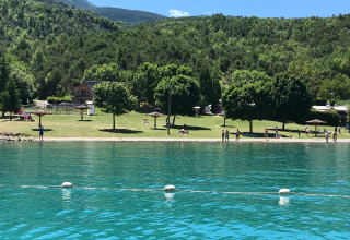 Feriepark Huttopia Lac de Serre Ponçon i Provence-Alpes-Côte d’Azur, Frankrig, med grønne bjerge og klar sø.