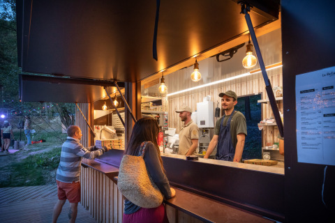 Eetstand bij Huttopia Lac de Serre Ponçon met bezoekers en medewerkers in Provence-Alpes-Côte d’Azur, Frankrijk.