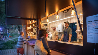 Puesto de comida en Huttopia Lac de Serre Ponçon con huéspedes y personal en Provence-Alpes-Côte d’Azur, Francia.