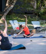 Dos mujeres hacen yoga al aire libre sobre esterillas en Huttopia Lac de Serre Ponçon, Francia.