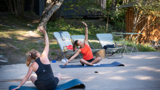 Dos mujeres hacen yoga al aire libre sobre esterillas en Huttopia Lac de Serre Ponçon, Francia.