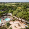 Aerial view of pools, playground, and greenery at Huttopia Chardons Bleus - Ile de Ré holiday park in France.