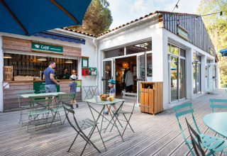 Buitencafé van Huttopia Chardons Bleus - Ile de Ré, met gasten en spelende kinderen in de zon.