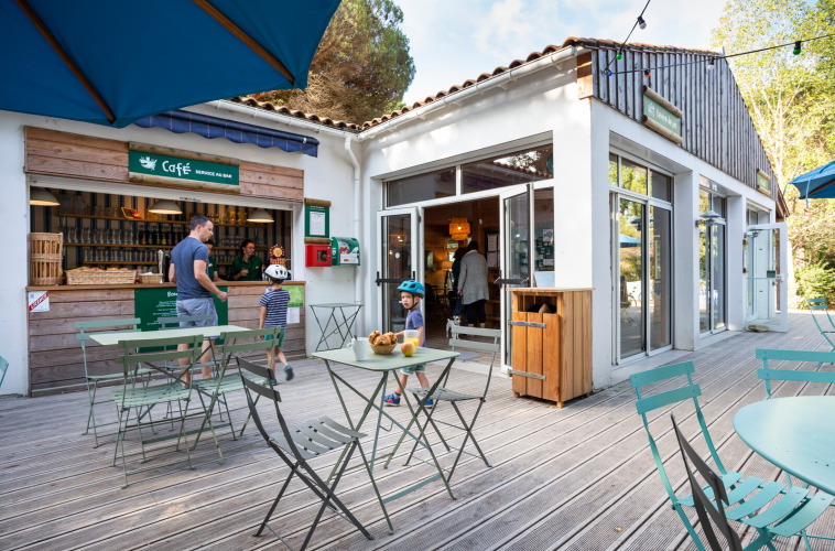 Espace café extérieur au Huttopia Chardons Bleus - Ile de Ré, avec des clients et des enfants en terrasse.