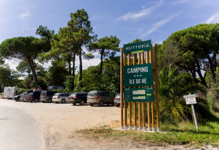 Ingang van Huttopia Chardons Bleus - Île de Ré met auto's en bomen in Nouvelle-Aquitaine vakantiepark.
