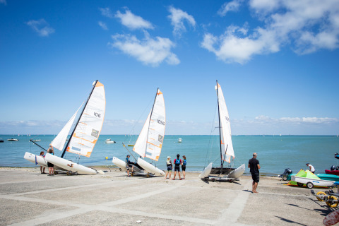 Navegantes preparan catamaranes en la playa de Huttopia Chardons Bleus - Ile de Ré, Nouvelle-Aquitania, Francia.