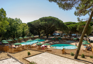 Zona de piscina al aire libre con sombrillas verdes y valla de madera en Huttopia Chardons Bleus - Ile de Ré, Francia.