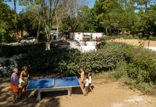 Mensen spelen tafeltennis buiten op een vakantiepark omringd door groen bij Huttopia Chardons Bleus, Ile de Ré.