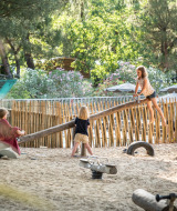 Niños jugando en un balancín en el parque infantil arenoso de Huttopia Chardons Bleus - Ile de Ré, Francia.