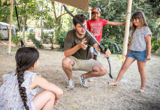 Ein Erwachsener unterrichtet Kinder im Bogenschießen auf einem Campingplatz bei Huttopia Chardons Bleus - Ile de Ré.
