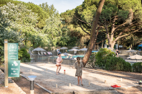 Niños juegan a la petanca en una pista de arena en Huttopia Chardons Bleus - Ile de Ré, rodeados de naturaleza.
