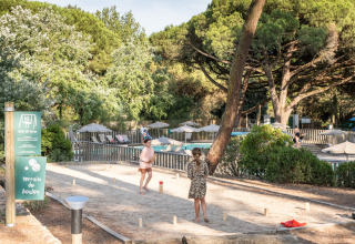 Kinderen spelen pétanque op een zandveld bij Huttopia Chardons Bleus - Ile de Ré, omgeven door bomen.
