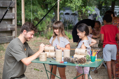 Kinderen doen knutselactiviteiten met een begeleider bij Huttopia Chardons Bleus - Ile de Ré in Frankrijk.