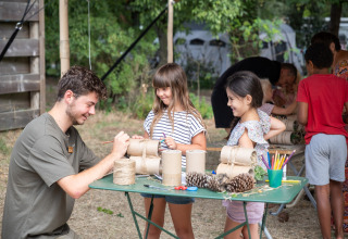 Kinder basteln draußen mit einem Erwachsenen im Huttopia Chardons Bleus - Ile de Ré in Frankreich.