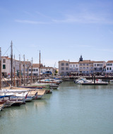 Barcos amarrados en un puerto pintoresco con edificios blancos en Sainte-Marie-de-Ré, Nouvelle-Aquitaine.