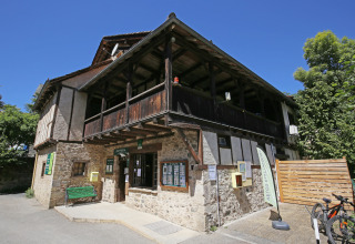 Edificio de piedra en el parque vacacional Huttopia Beaulieu sur Dordogne, Occitanie, Francia, bajo cielo azul.