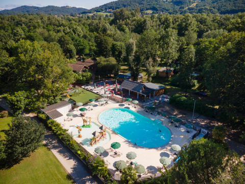 Vista aérea de la piscina y zona de juegos en Huttopia Beaulieu sur Dordogne, rodeado de naturaleza en Occitania.
