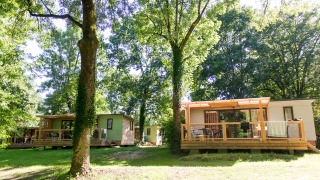 Mobilheim Vancouver bei Huttopia Beaulieu sur Dordogne in Frankreich, eingebettet in grüne Bäume.