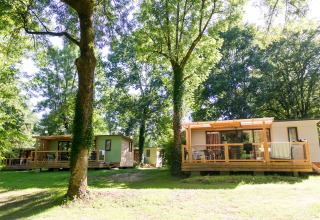 Mobilheim Vancouver bei Huttopia Beaulieu sur Dordogne in Frankreich, eingebettet in grüne Bäume.