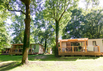 Casa móvil Vancouver en Huttopia Beaulieu sur Dordogne, Francia, rodeada de árboles verdes y naturaleza.