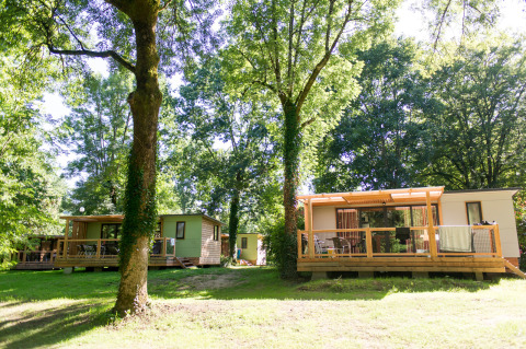 Mobile home Vancouver à Huttopia Beaulieu sur Dordogne en France, entouré d'arbres et de nature verdoyante.