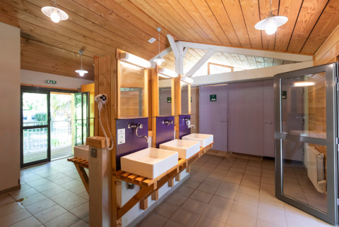 Instalaciones de baño comunitario moderno con techo de madera en Huttopia Beaulieu sur Dordogne, Occitanie, Francia.