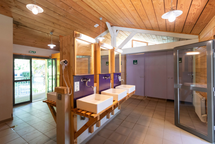 Moderne Gemeinschaftsbadezimmer mit Holzdecke in Huttopia Beaulieu sur Dordogne, Occitanie, Frankreich.