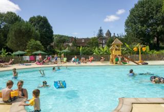 Børn og familier nyder en udendørs swimmingpool med legeområde på Huttopia Beaulieu sur Dordogne.